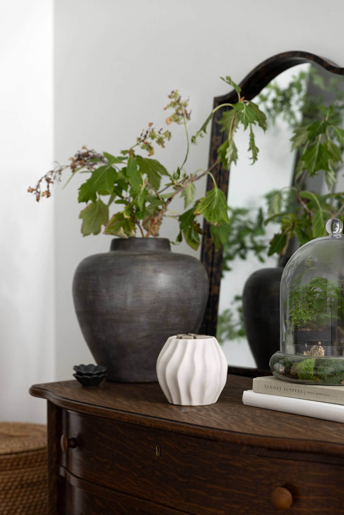 Cascade Warmer in matte white ceramic with soft sculpted curves, styled on a wooden console table beside greenery and decorative accents in a warm, neutral home setting.