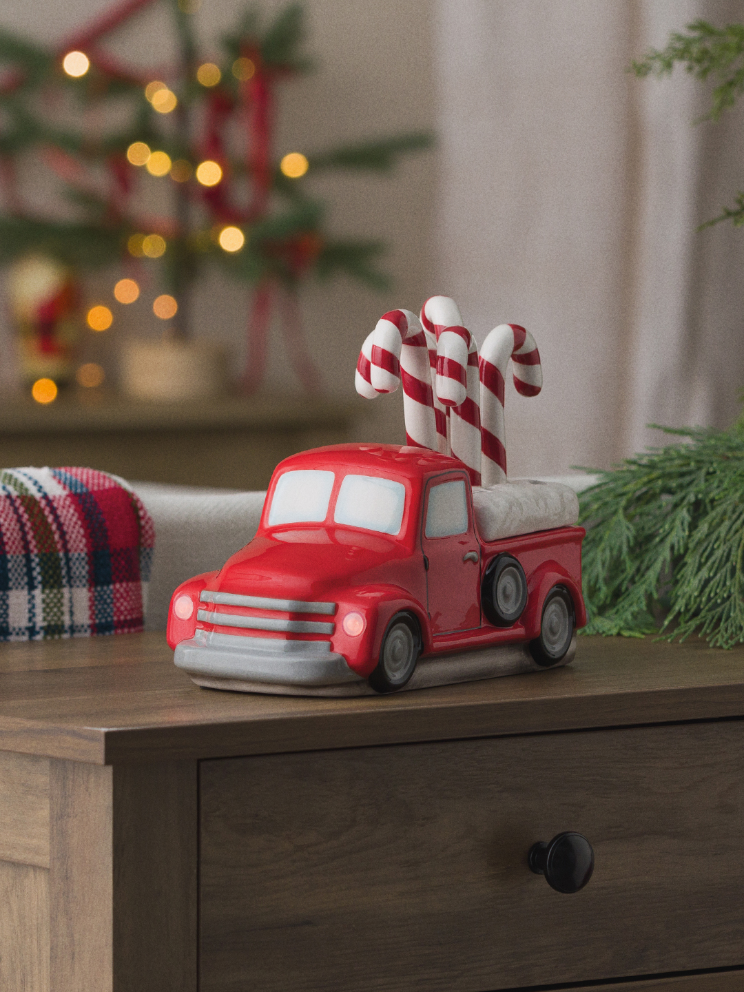 A Red Retro Truck Warmer with Candy Cane Topper is displayed in a living room decorated for the holidays.