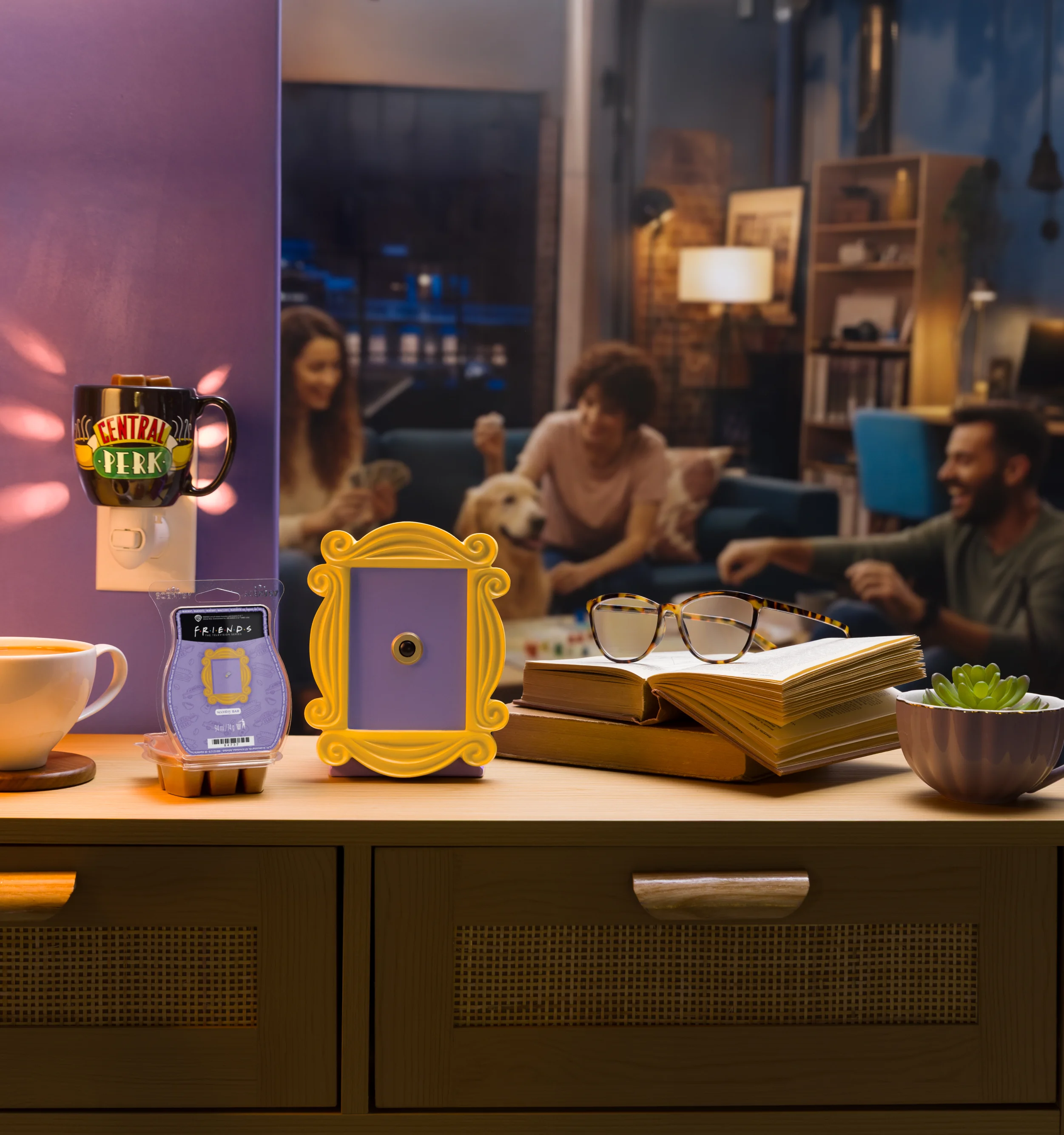 Produkte der Kollektion Friends sind zusammen mit einer Kaffeetasse, Büchern und einer Brille abgebildet. Menschen unterhalten sich im Hintergrund.