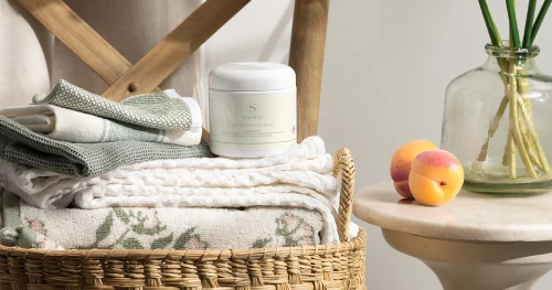 Scentsy Wassen producten gepresenteerd in een gevlochten mand met opgevouwen linnengoed in een zachte, natuurlijke woonomgeving.