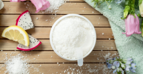 A container of Washer Whiffs with a scoop rests on a wooden slatted table, surrounded by vibrant fruits and florals.