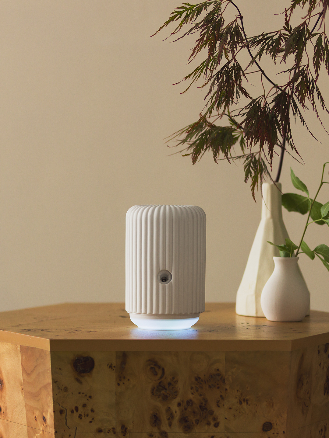 A hand holds a phone displaying the Scentsy Solo app beside the Scentsy Fragrance Cartridge Diffuser - Solo.