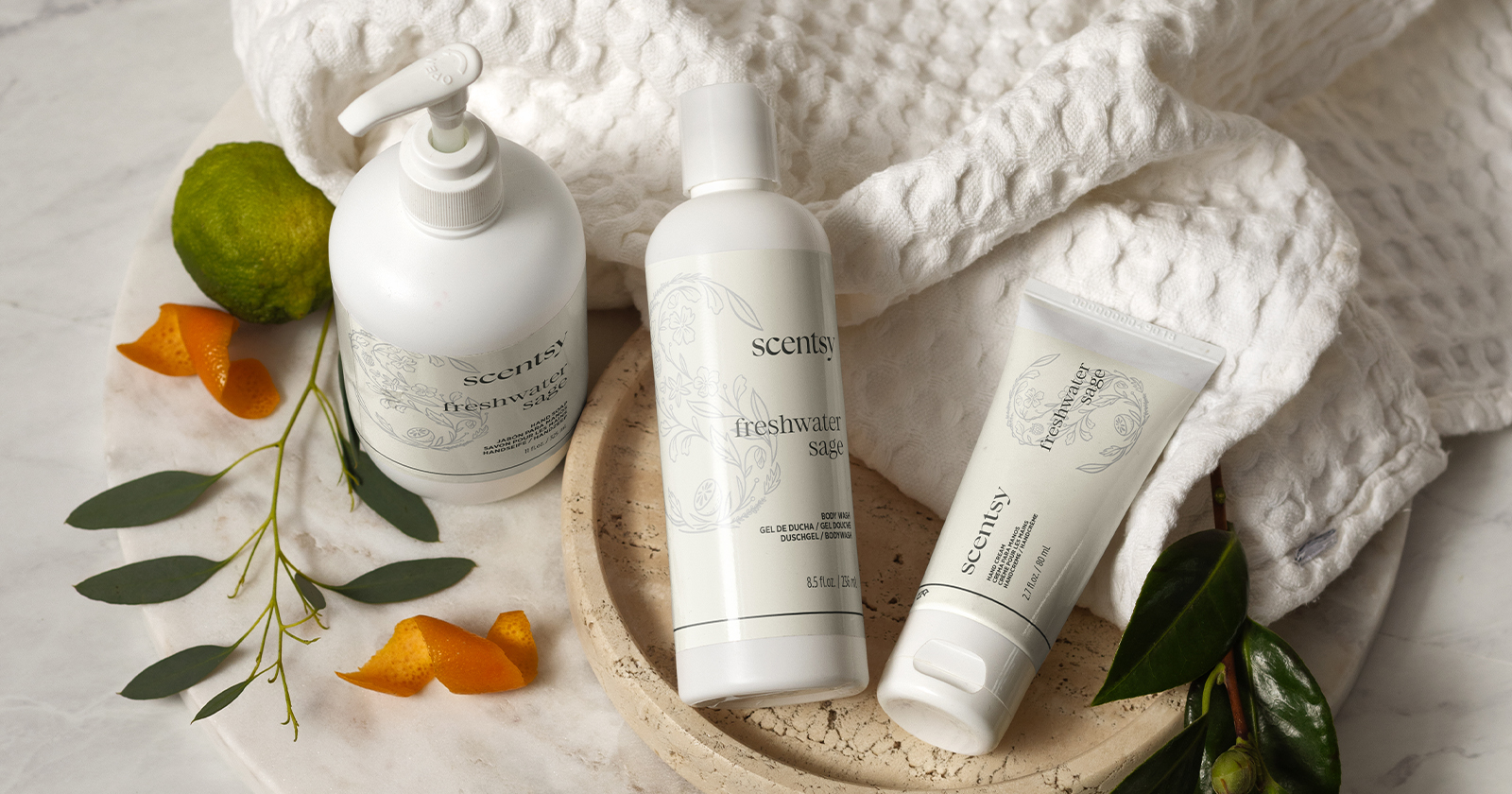 Scentsy body care products displayed on a soft towel with natural accents in a bright, spa-inspired setting.