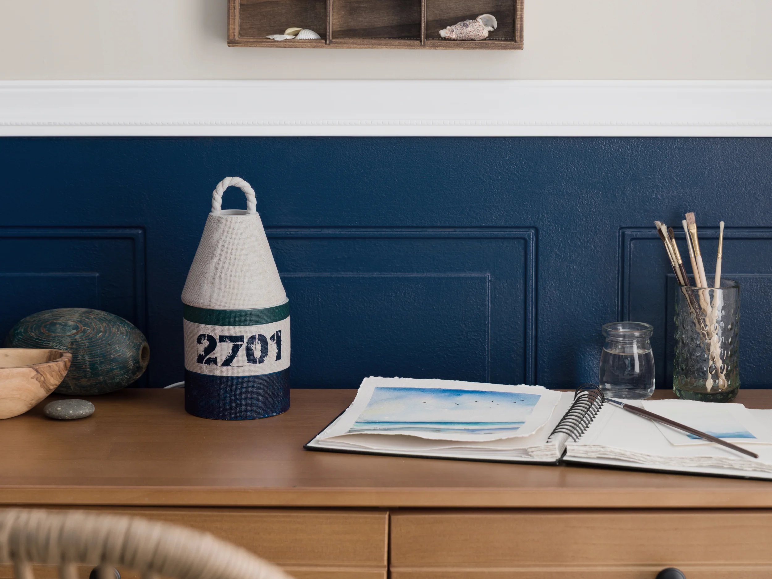 A Bay Buoy Warmer is displayed on a desk next to a notebook and coastal décor.