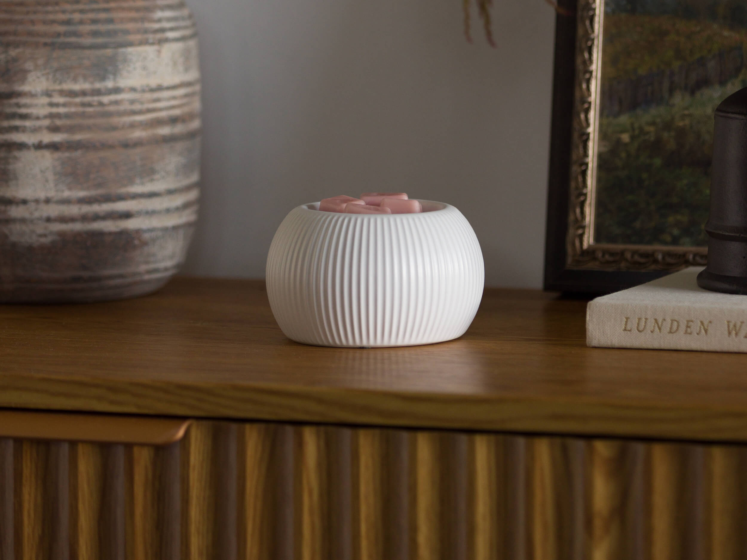 A Scentsy fragrance oil bottle is showcased with flowers against a dreamy green backdrop.