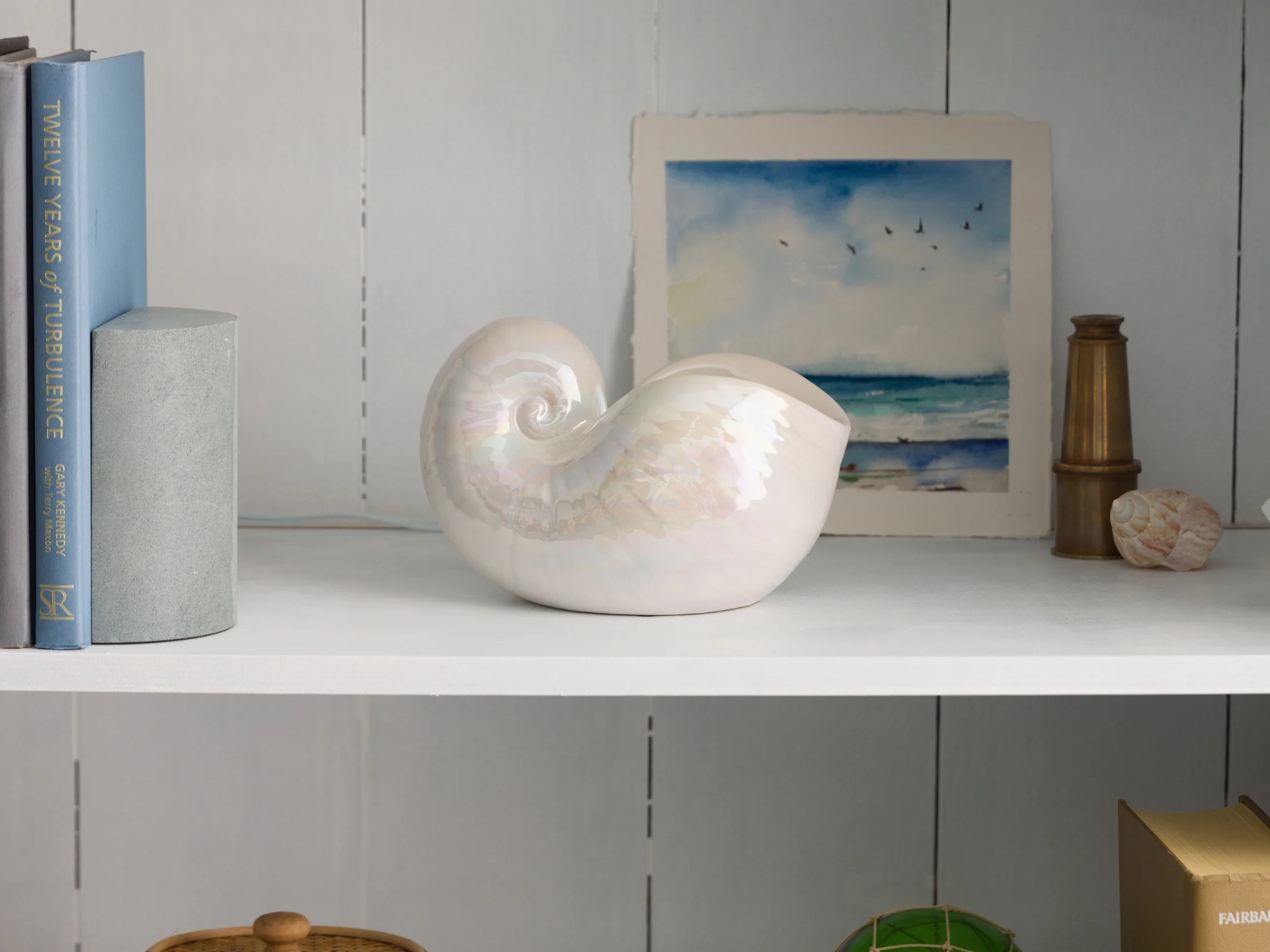 A Bay Buoy Warmer is displayed on a desk next to a notebook and coastal décor.