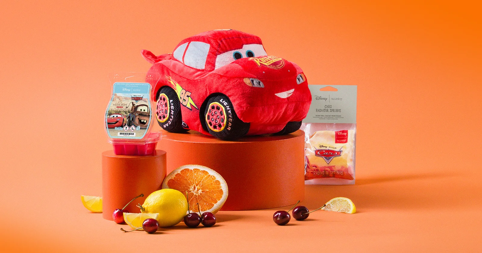Disney and Pixar Cars Collection products are displayed on risers with fruit against an orange background.