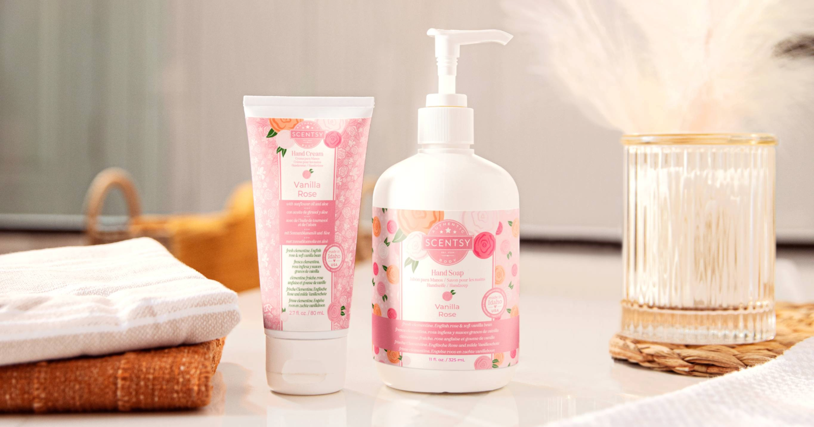 Scentsy Vanilla Rose body wash in white bottle with pink floral label on gray countertop, styled with wooden brush, pink flowers, and blurred bathroom accessories