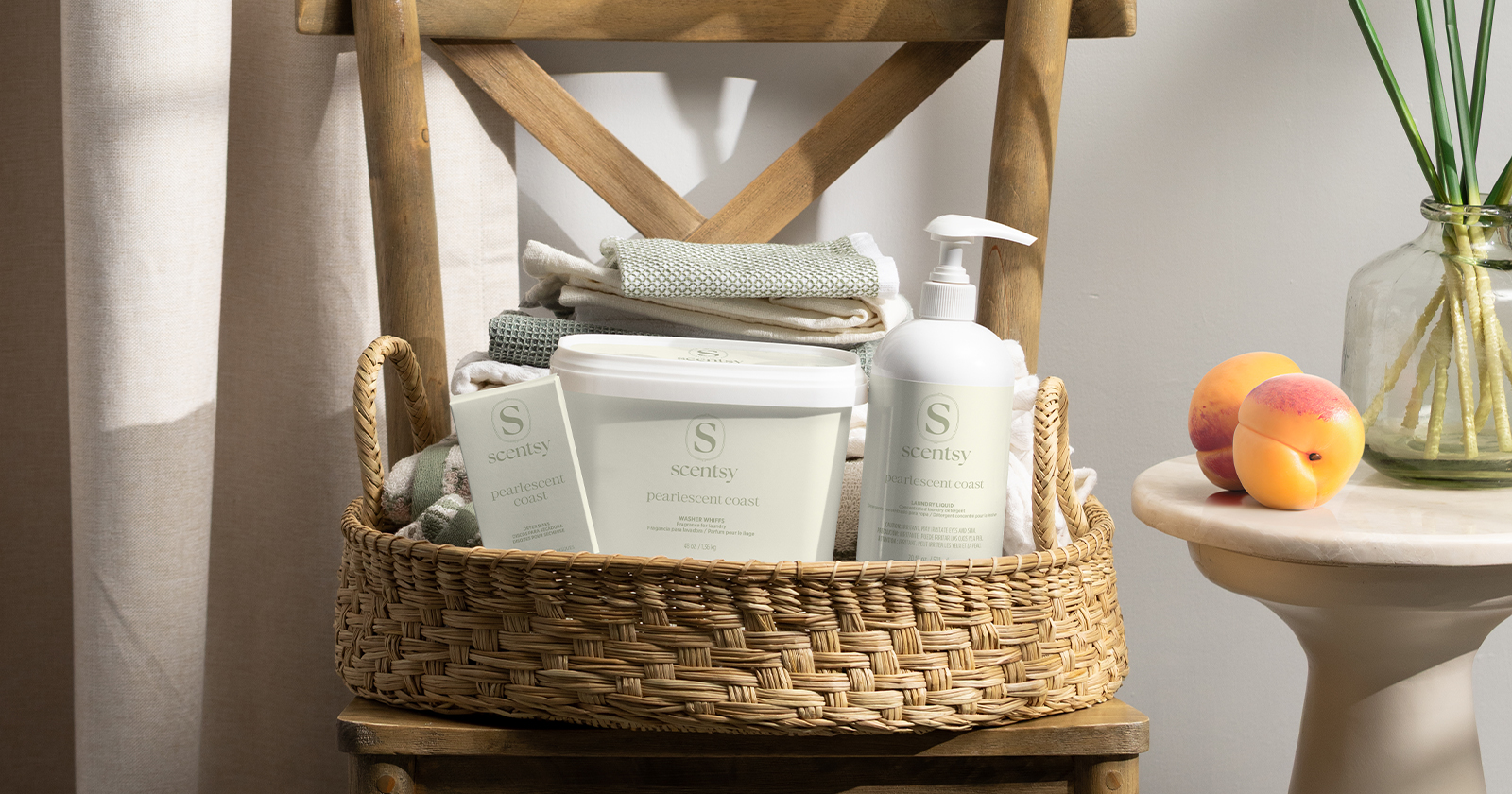Scentsy laundry products displayed in a woven basket with folded linens in a soft, natural home setting.
