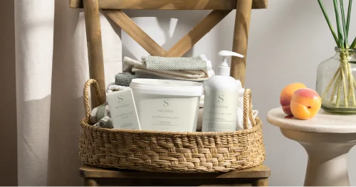 Scentsy laundry products displayed in a woven basket with folded linens in a soft, natural home setting.