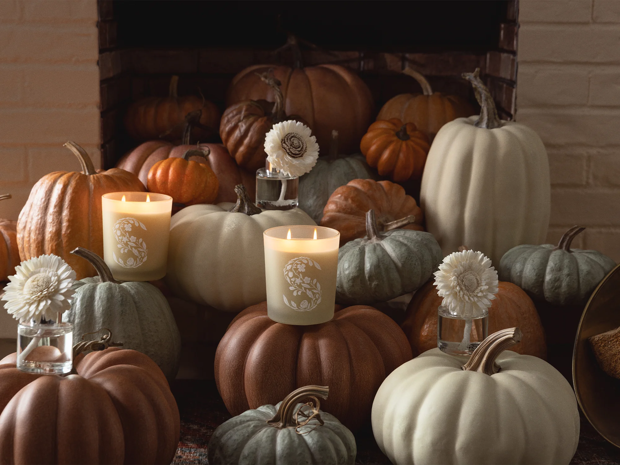 Candles and Fragrance Flowers shown with a tableau of pumpkins in front of a fireplace