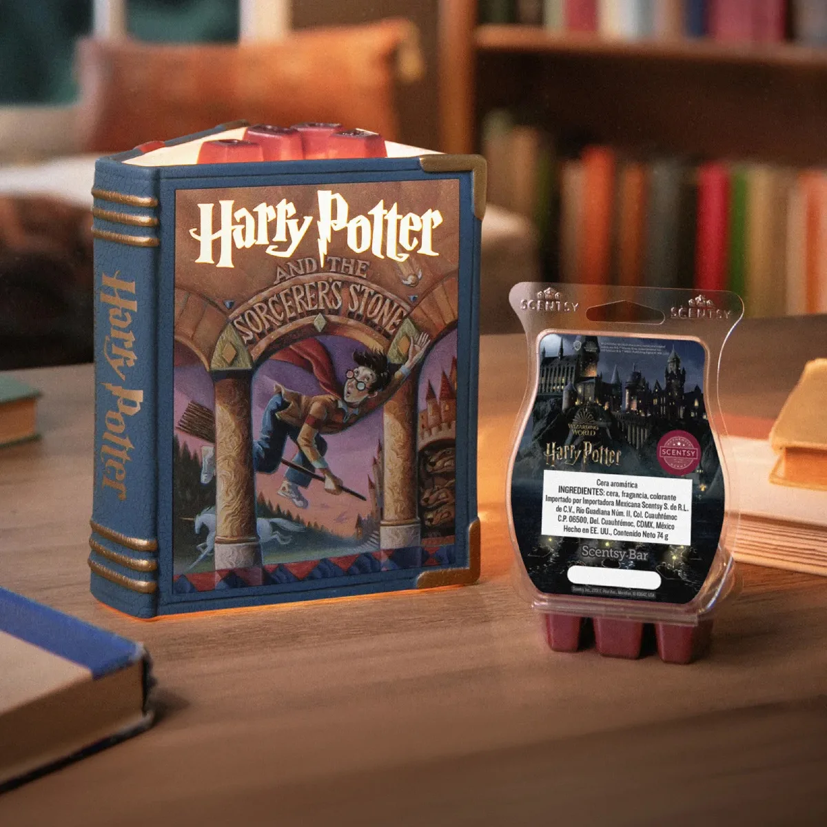 Un Calentador Scentsy – Harry Potter and the Sorcerer’s Stone y la Barra Scentsy – Wizarding World: Harry Potter entre unos libros en una mesa de centro que está en un rincón para leer. 