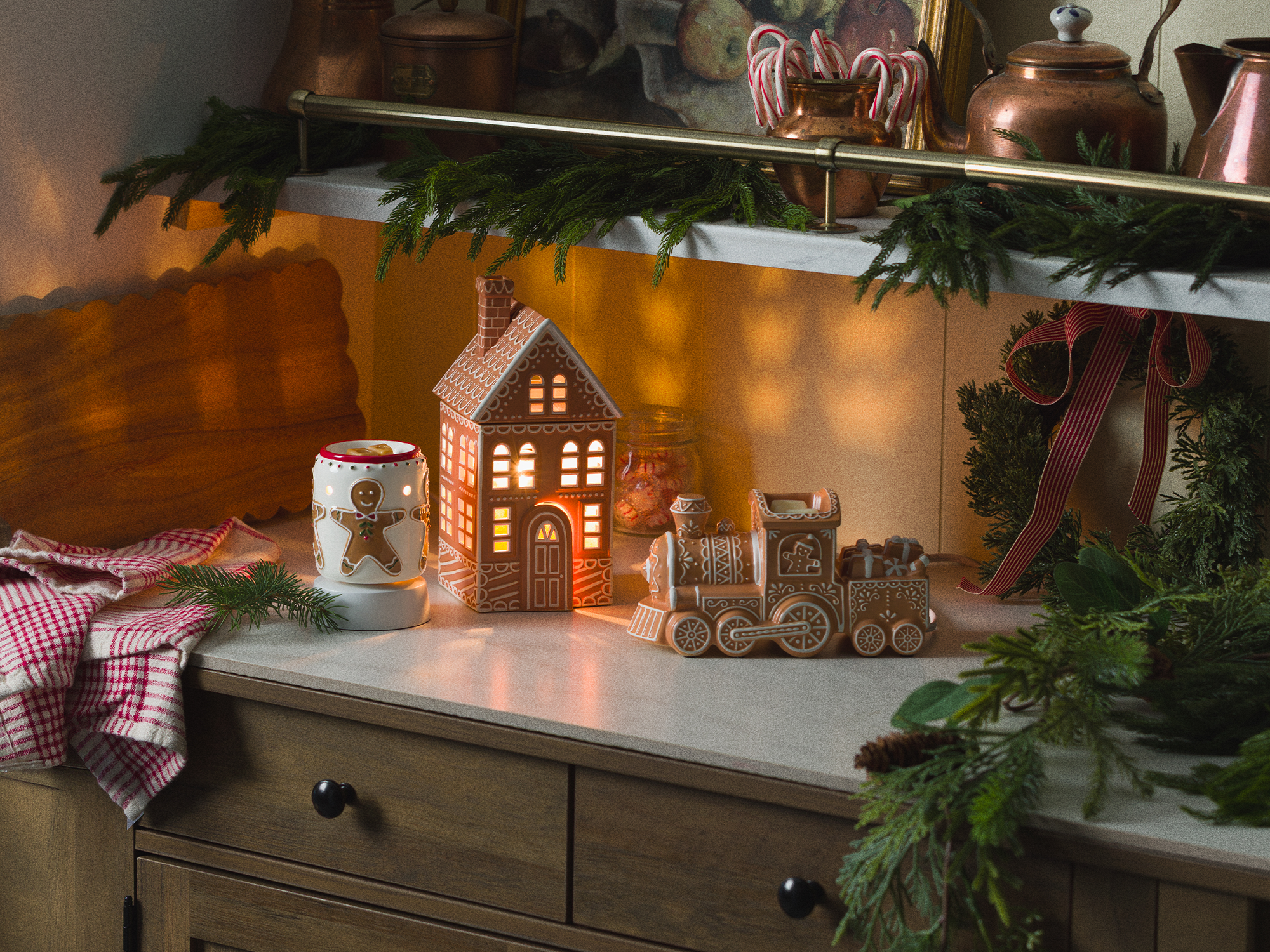 Drei Duftlampen aus dem Monatsspecial: Lebkuchen, ausgestellt in einer Küche mit Tannengirlande und rot-weißen Akzenten.