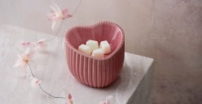 A Heart of Hope Warmer is displayed on a marble surface with a floral garland.