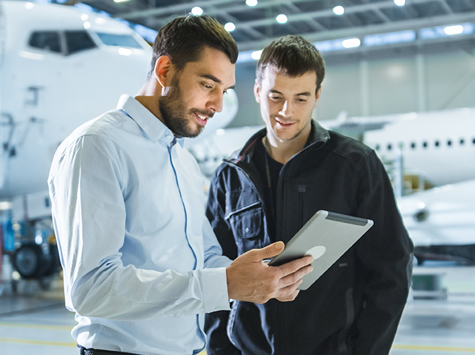 Two people people in the freight business working with a mobile device in an airplane hangar.