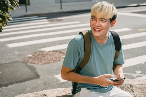 A boy with dyed hair sending an SMS message on his mobile phone