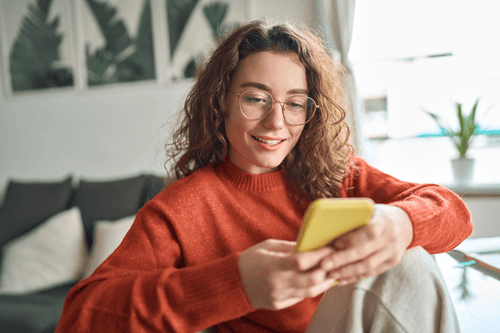 stock-photo-young-smiling-woman-wearing-glasses-holding-smartphone-using-cellphone-modern-technology-looking ransformed