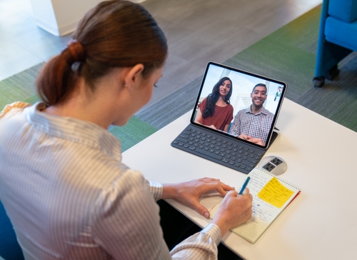 A female employee communicating with business colleagues on a video call using CCaaS tools on a laptop.