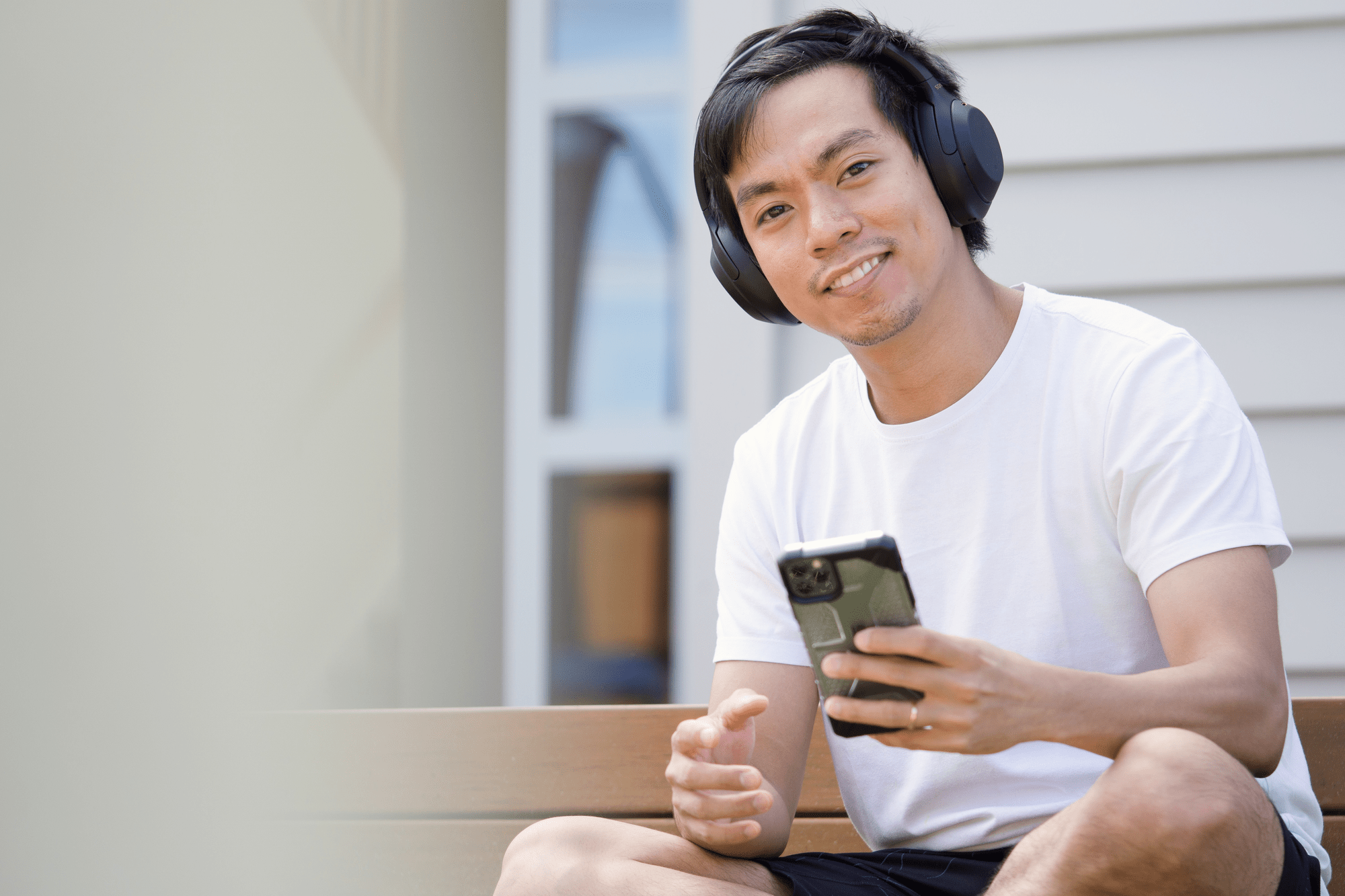 Man smiling with headphones on while holding a phone