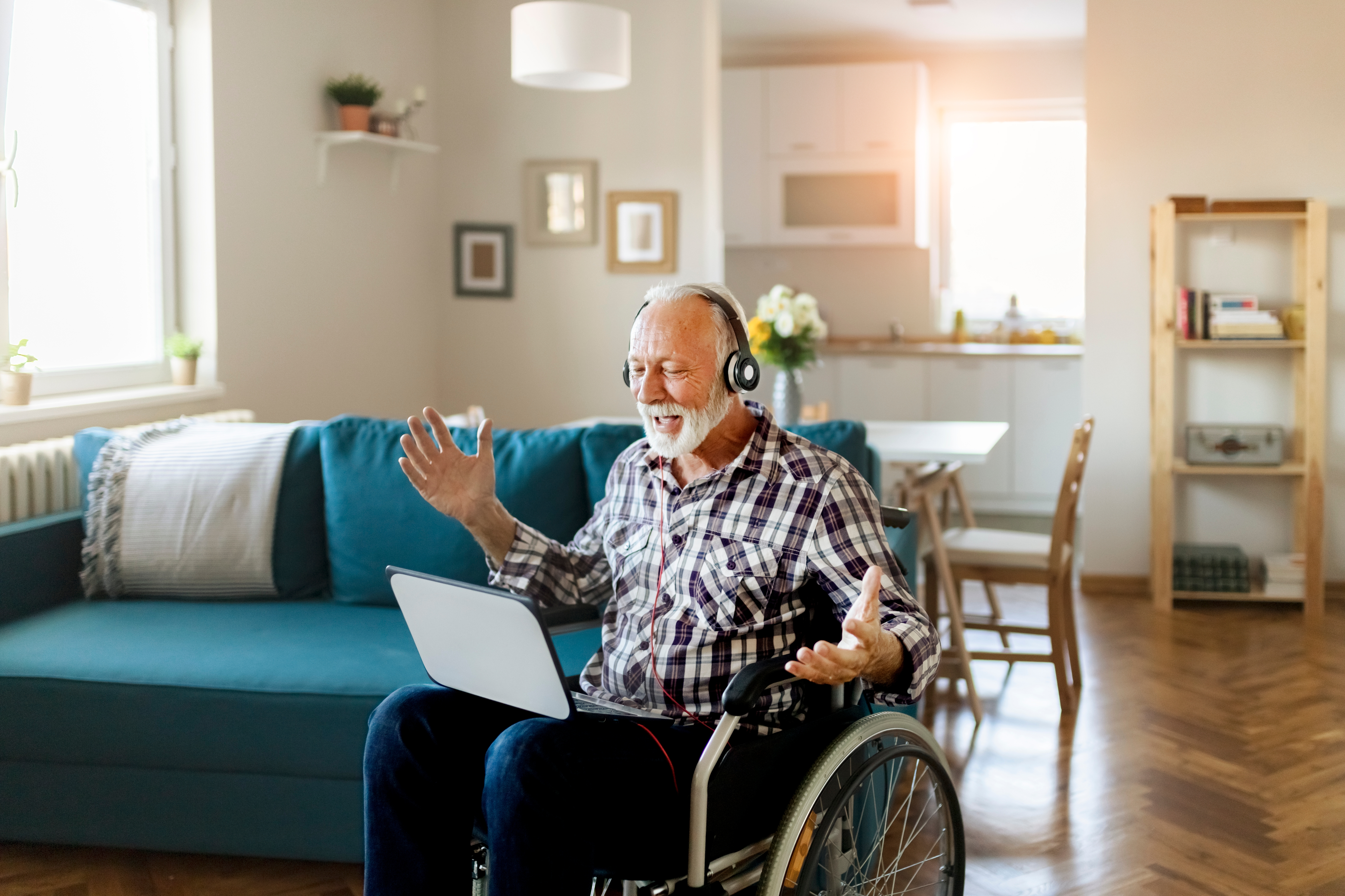 Pria lanjut usia di kursi roda berbicara melalui video call di rumah