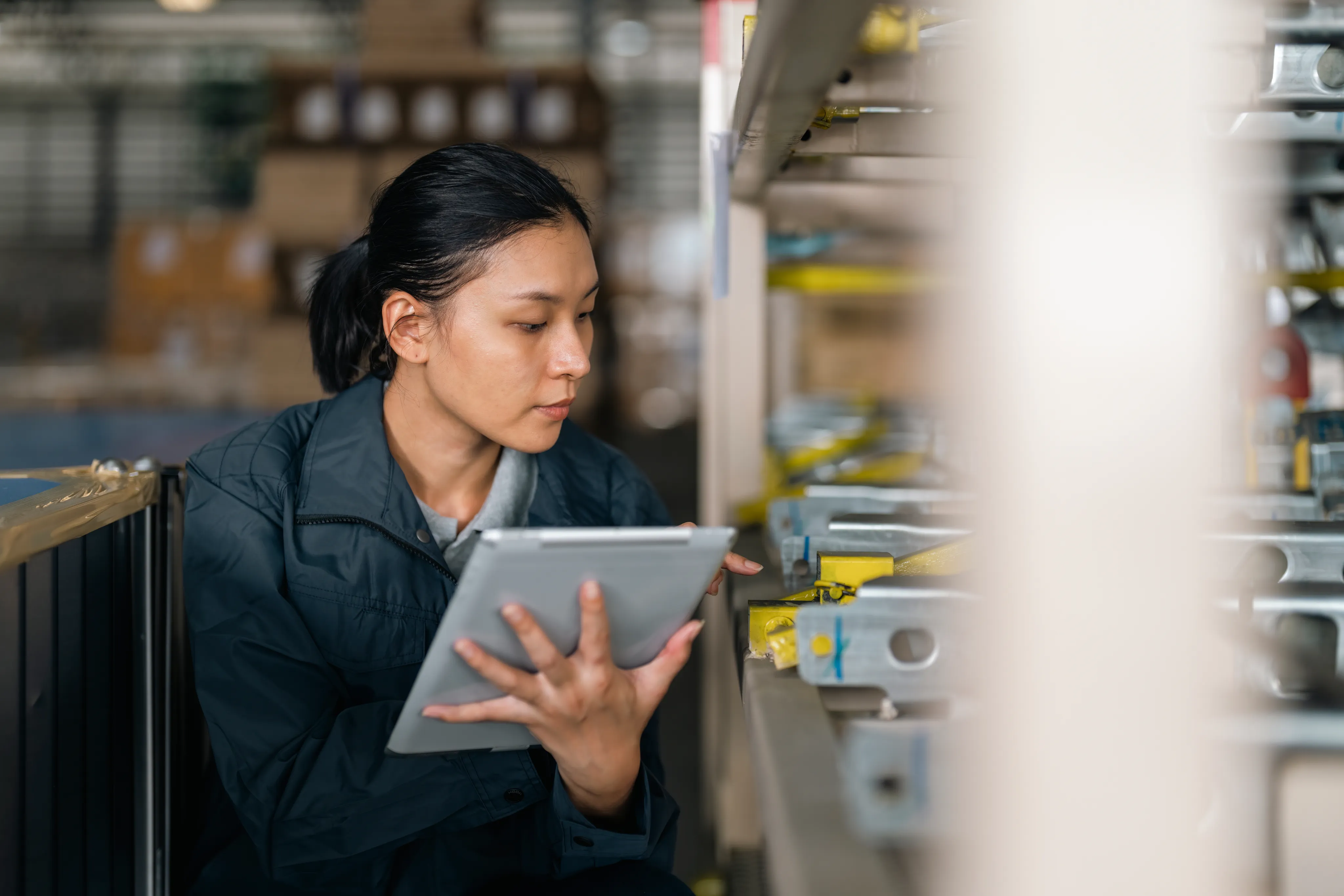 Woman taking inventory of items on a shelf with a tablet.