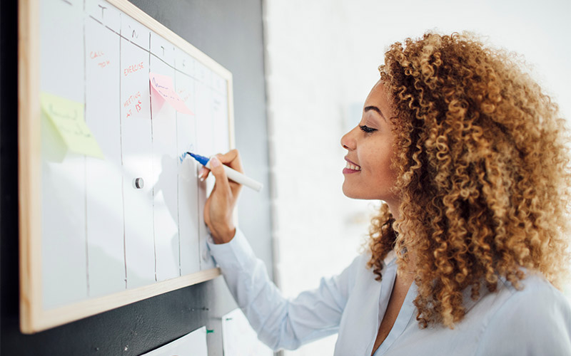 A woman writing notes on a whiteboard.