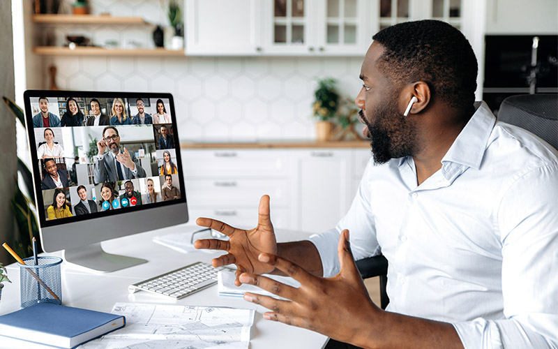 A man sits in front of a computer while on a virtual meeting call.