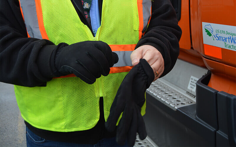 A truck driver slips on a pair of winter gloves.