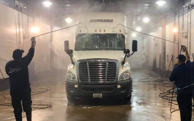 Truck wash facility employees show how to wash a semi truck.
