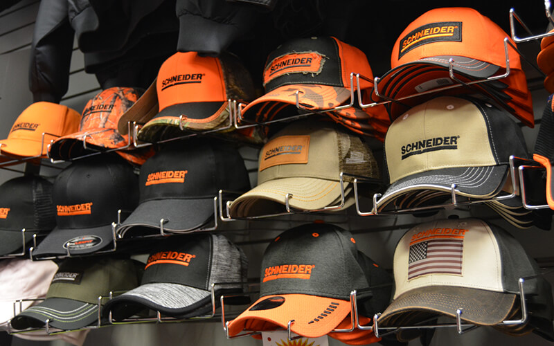 Schneider baseball caps are organized in a rack along the wall of the company store.