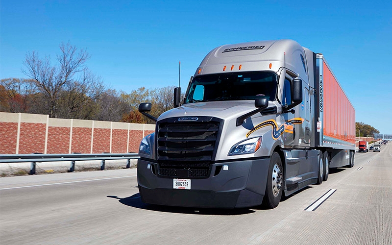 A grey Schneider semi-truck driving on a highway.