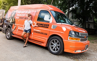 Lindsay Lawler gestures to the Schneider logo on an orange company van during her Highway Angel Truckstop Tour 