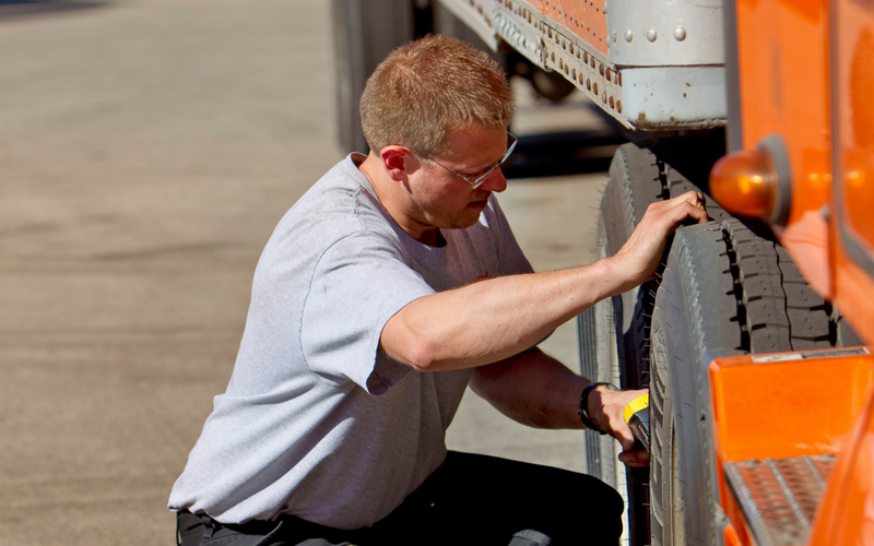 A Schneider driver checking his tire pressure.