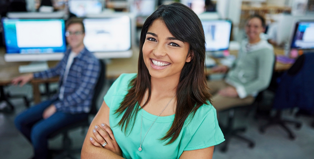 A female Schneider associate smiles and poses confidently in a busy office area
