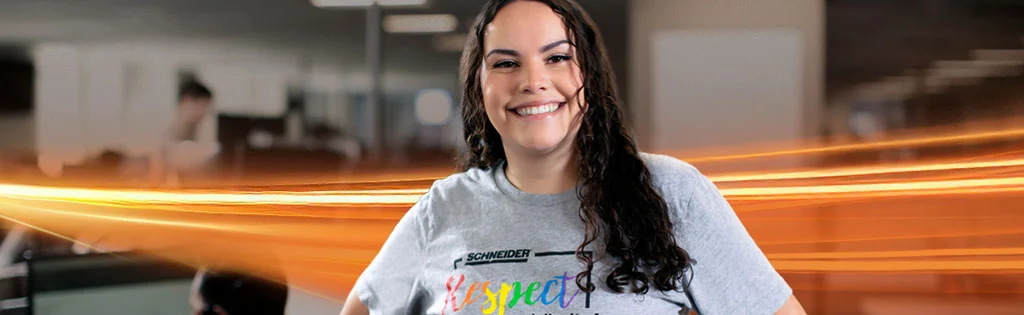 A female Schneider associate smiles in a busy office area