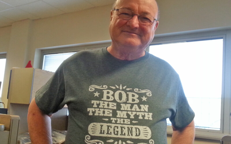 Bob at a Schneider facility wearing a t-shirt that reads "Bob: the man, the myth, the legend."