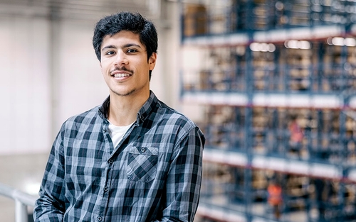 A man standing in a warehouse smiling.