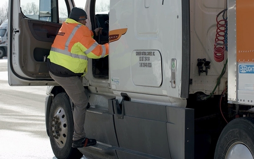 A Schneider driver instructor climbing into their cab using three points of contact.