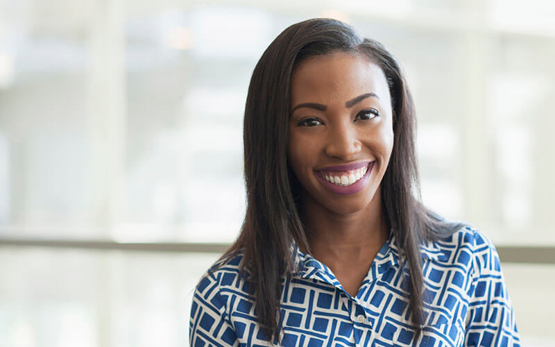 A smiling young professional poses for a professional headshot at her first job after graduating college.