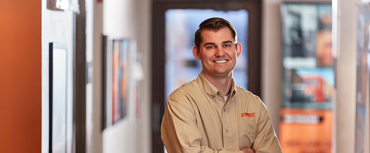 A Schneider sales associate smiles while posing confidently at a Schneider facility 