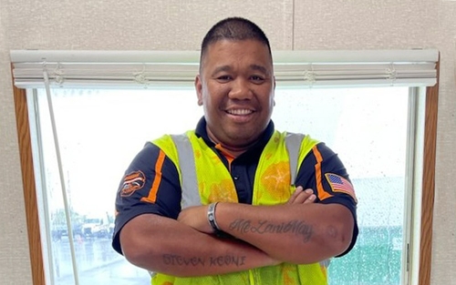 Dennis Yutuc wearing his yellow safety vest covered in palm trees and flowers.