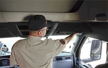 Driving Instructor Brett demonstrates where the overhead compartments are on passenger's side of a semi-truck.