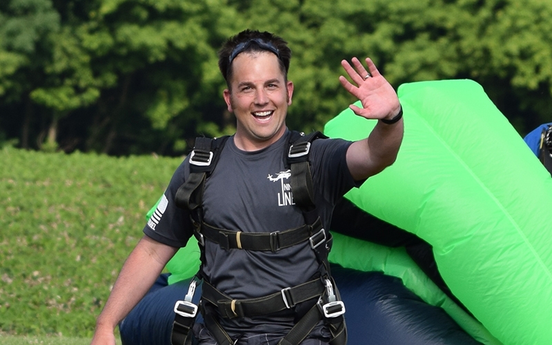 Josh waves shortly after landing with his harness and parachute still attached.