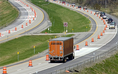 A Schneider truck driver proceeds cautiously through a road construction zone.