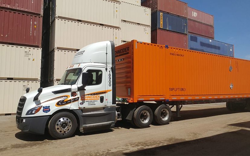A Schneider semi-truck delivering an intermodal container to a rail yard. 