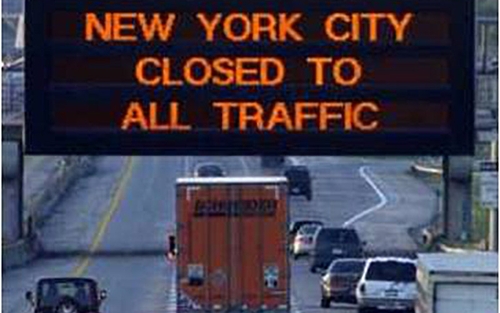 Schneider truck on highway driving under a sign that says "New York city closed to all traffic"