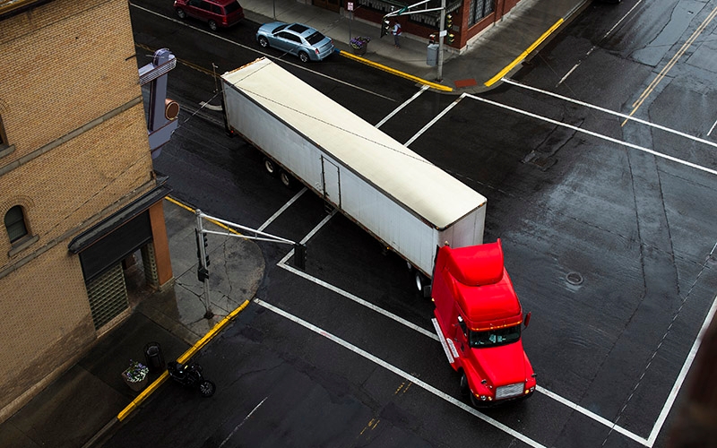 A semi-truck making a right turn at an intersection in a city. 