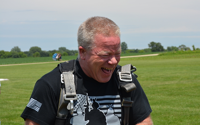 Chip laughs in his skydiving harness shortly after landing.