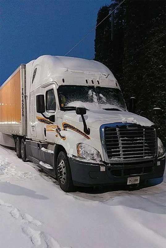 A Schneider company truck covered in a light layer of snow.