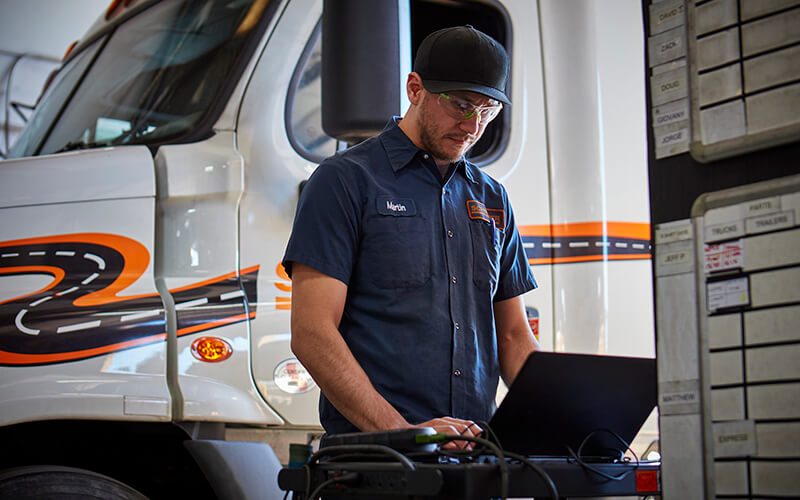 Schneider diesel technician working on the computer near his service bay.